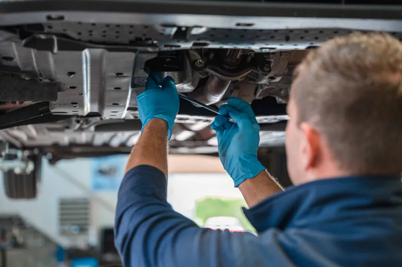 Meccanico dell'officina Trieste Auto di Muggia (Trieste) al lavoro sotto un'auto sollevata sul ponte durante un tagliando